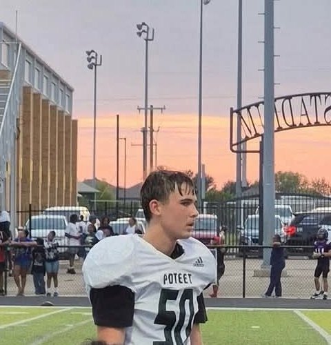 Daylen Shain on the sideline at sunset in his white Poteet number 50 jersey